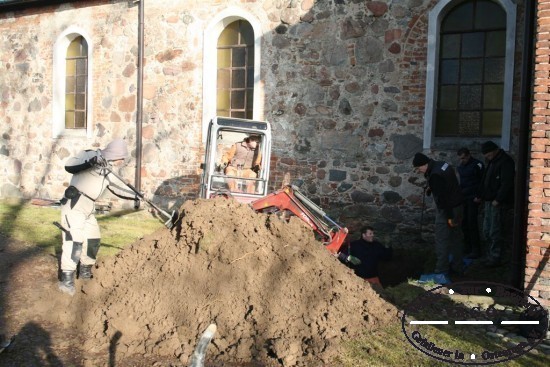 Die Grablage ist gefunden. Die obere Bodenschicht wird mit schwerem Gert abgetragen.